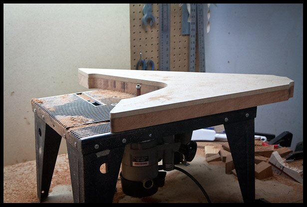Routing the body shape on the router table with the MDF template as a guide